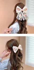 Detail view of lace bow hair clips with delicate rose embroidery and long ribbons