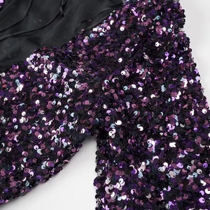 Close-up of purple sequins on long sleeve party dress showing detail of shiny texture