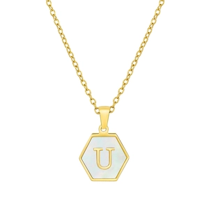 Macro detail of hexagonal gold pendant featuring white shell inlay and letter U engraving