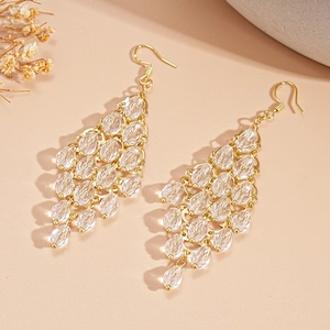 Macro detail of elegant golden earrings with layered clear crystal beads and drop fringe