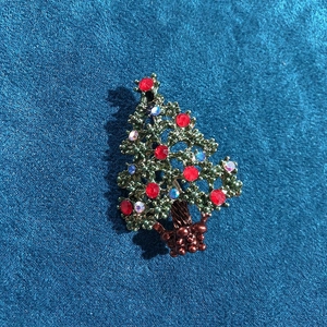 Detailed view of a vintage Christmas tree brooch with red gems and rhinestones