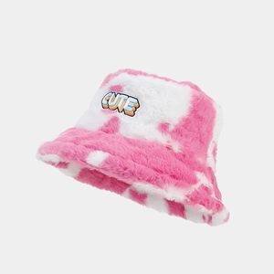 Détail d'un bob en peluche à motif vache rose avec écusson brodé CUTE arc-en-ciel