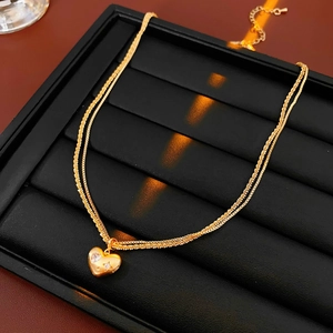 Gros plan d'un collier double en or avec pendentif en forme de cœur serti de pierres