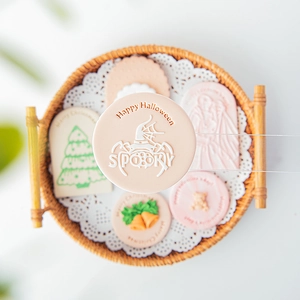 Acrylic fondant stamp pressing Happy Halloween design on pink cookie dough for baking