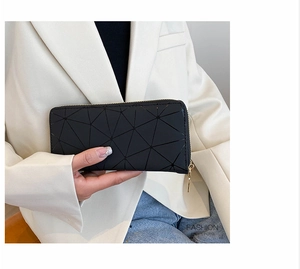 Close-up of model holding a black geometric triangle patterned long wallet with zipper