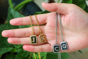 Detail of gold and silver letter pendants J, N, C, Q with sparkling zircon stones