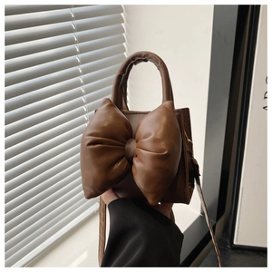 Detail of a brown PU leather crossbody bag with a large padded bow and top handle