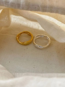 Detailed view of stackable gold and silver wavy rings with a liquid ripple texture