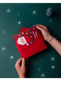 Hands pulling a 3D cartoon Santa Christmas card from a red envelope on green background