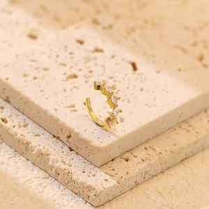 Detailed shot of S925 sterling gold ear cuff with five square zircons on beige stone