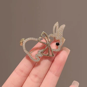 Golden rabbit brooch with sparkling rhinestones and a stylish bow design held by a hand
