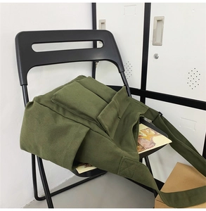 Detail view of army green canvas crossbody bag with flap cover and utility pockets