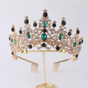 Close-up of golden birthday crown with green and black gemstones on a display stand