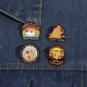 Four capybara enamel pins styled on denim fabric showcasing detailed metal craftsmanship