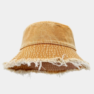 Close-up of ginger yellow washed denim bucket hat with distressed frayed edge details