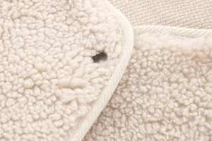 Macro shot of creamy teddy fleece fabric texture with detailed buttonhole and stitching