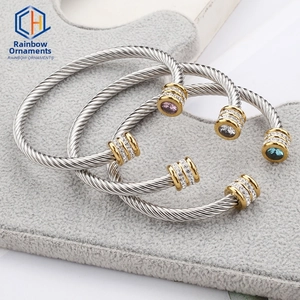 Macro detail of silver cable twist bracelets with gold accents and colorful gemstones
