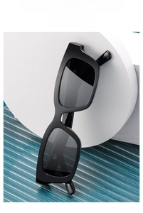 Macro view of black square frame sunglasses on wave texture with blue backdrop