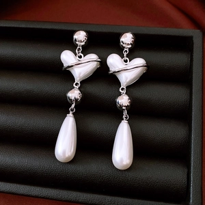 Detail of vintage silver heart earrings with pearl drops on a black jewelry box