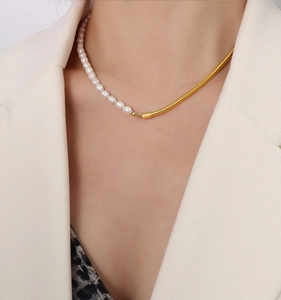 Macro shot of 18K gold snake chain and white pearl necklace on woman's neck