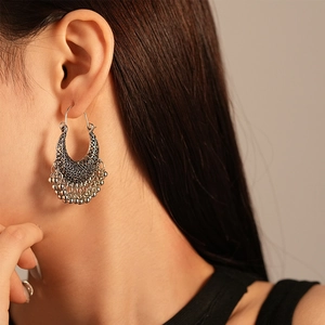 Gros plan sur une boucle d'oreille rétro argentée avec motifs ajourés et pampilles perlées