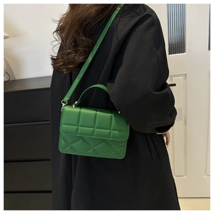 Detail of green crossbody bag with diamond lattice texture and adjustable strap