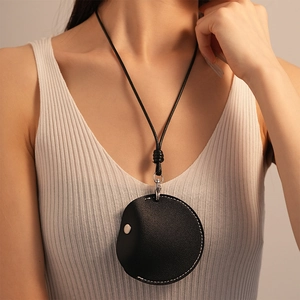 Detail of black faux leather mini bag necklace with white stitching and silver snap