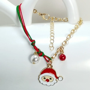 Detail of Christmas bracelet featuring Santa Claus charm, red and green braided rope, and beads
