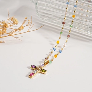 Macro view of gold-plated cross pendant with colorful crystals on a beaded chain
