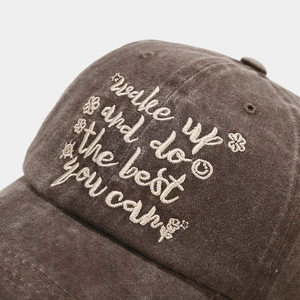 Macro detail of vintage brown cotton baseball cap with white floral embroidery and text