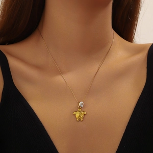 Gold-plated stainless steel necklace with turtle pendant and white bead on a model