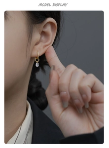 Detail showing a gold-plated teardrop crystal pendant earring worn by a model