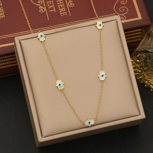 Detail of gold Hamsa Hand and Evil Eye pendants on a stainless steel necklace chain