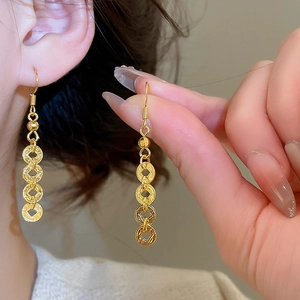 Close-up of golden coin-shaped drop earrings featuring a vintage four-circle link design