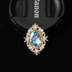 Macro shot of oval vintage alloy brooch with colorful gemstone and white rhinestones