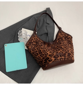 Close-up of leopard print hobo bag with leather base on a grey blazer background