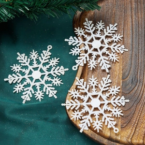 Close-up of three white glitter snowflake ornaments on a rustic wooden tray decoration