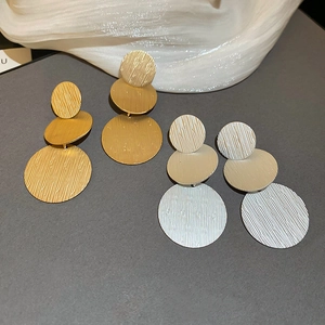 Macro shot of geometric brushed metal earrings in gold and silver with triple disc design