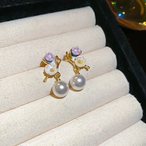 Détail de boucles d'oreilles fleurs lavande et perles blanches sur métal doré