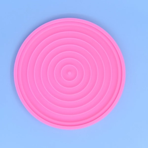 Pink round silicone cake mold with concentric circular ribs on light blue background