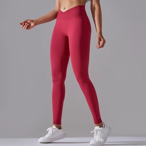 Detail showing the cross-over V-waistband and ribbed texture on rose red yoga pants