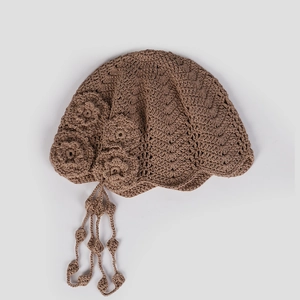 Detail of crochet beanie featuring handmade floral accents and elegant tassel charms