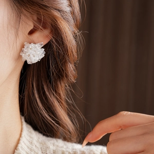 Close-up of white crystal bead cluster earrings worn by a model with soft lighting