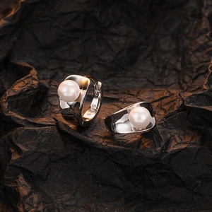 Elegant S925 sterling silver hoop earrings with white pearls on a textured black background