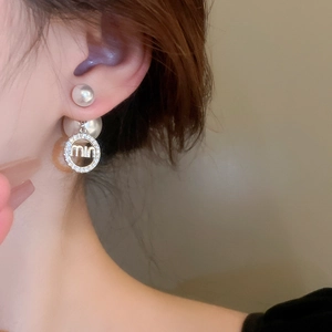 Detail of elegant two-way pearl earrings with rhinestone letter charm on model