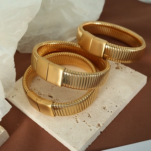 Vintage golden wide Tubogas stretch bracelets stacked on a minimalist stone pedestal