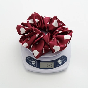 Detail view showing a large wine red heart pattern scrunchie on a digital scale weighing 13.0g