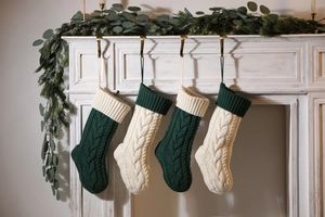 Detail of cable knit Christmas stockings in dark green and ivory hanging on fireplace