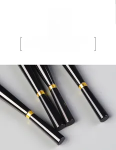 Detailed close-up of glossy black nail brush handle with golden metallic ring accents