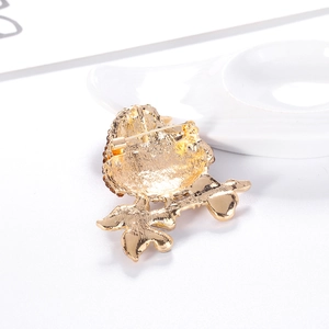 Golden alloy bird brooch back view with durable pin and branch design on white background